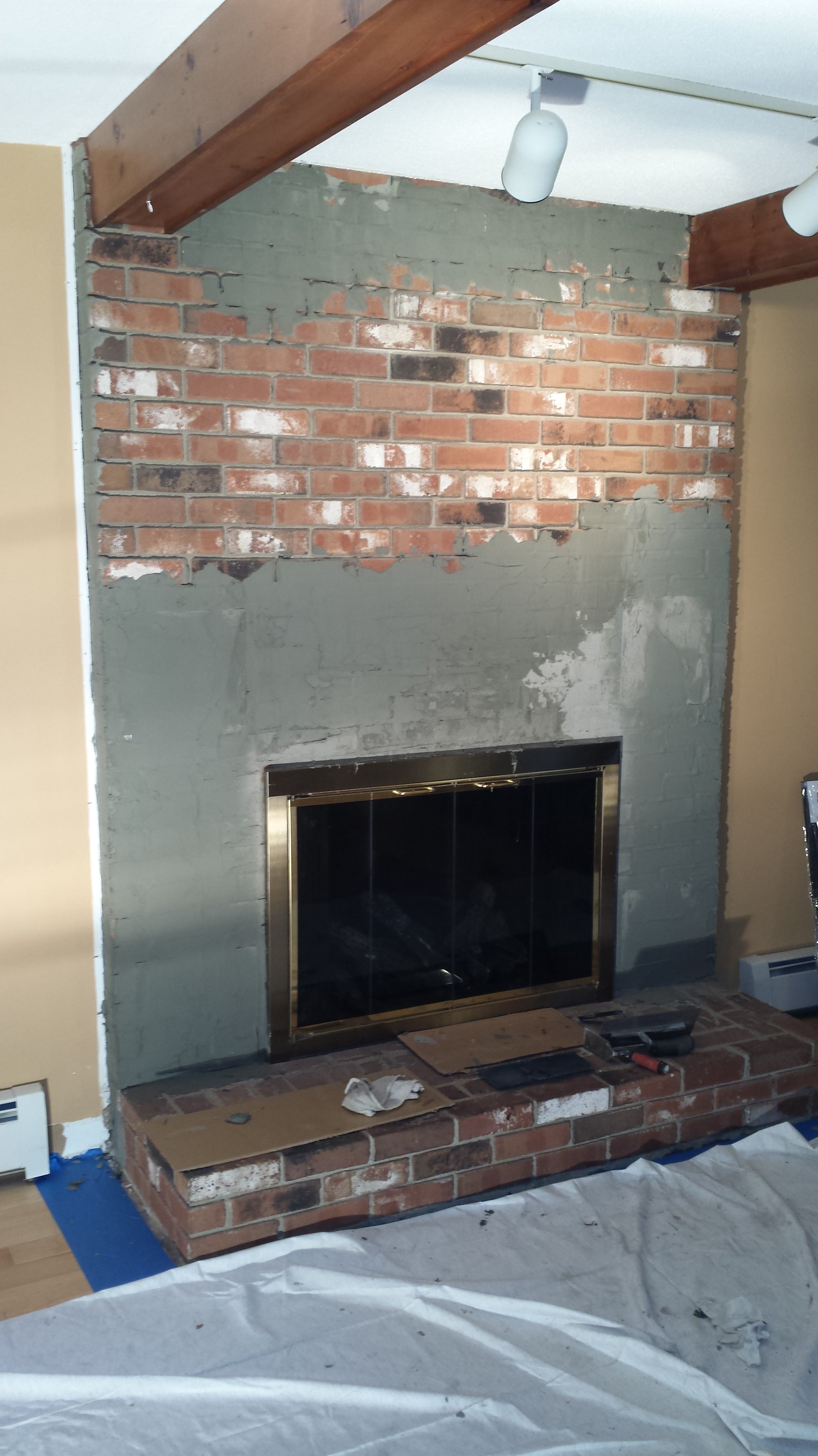 Old brick fireplace receiving a masonry skim coat to prep it for installation of Norstone Aztec XL Stone Veneer